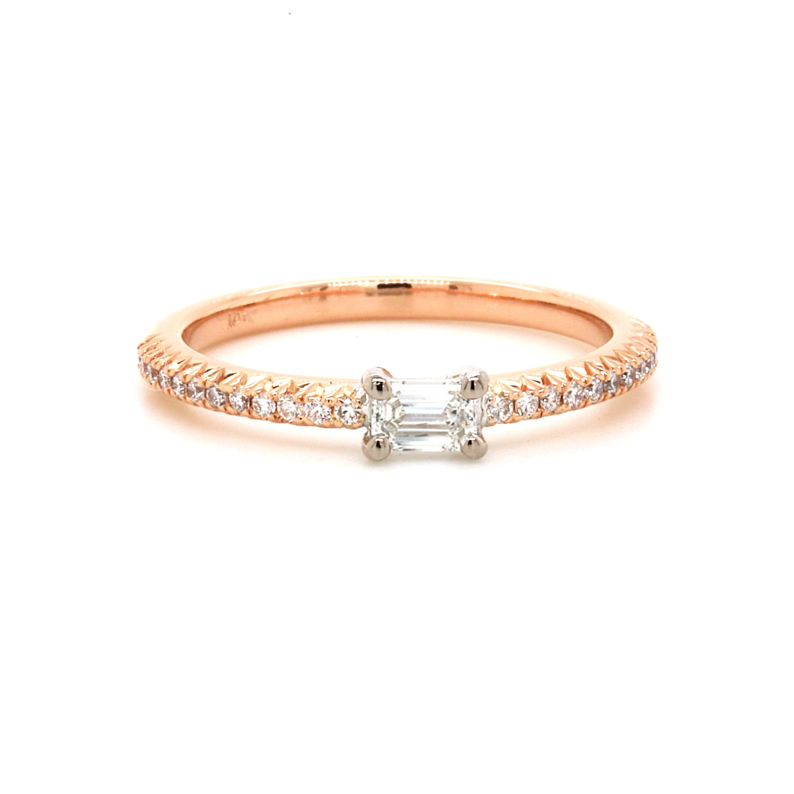 Engagement ring called 'Nikki' by Mark Nathan Jewellery. Rose gold band with centre emerald cut diamond. 12 smaller round diamonds on either side of the centre diamond.
